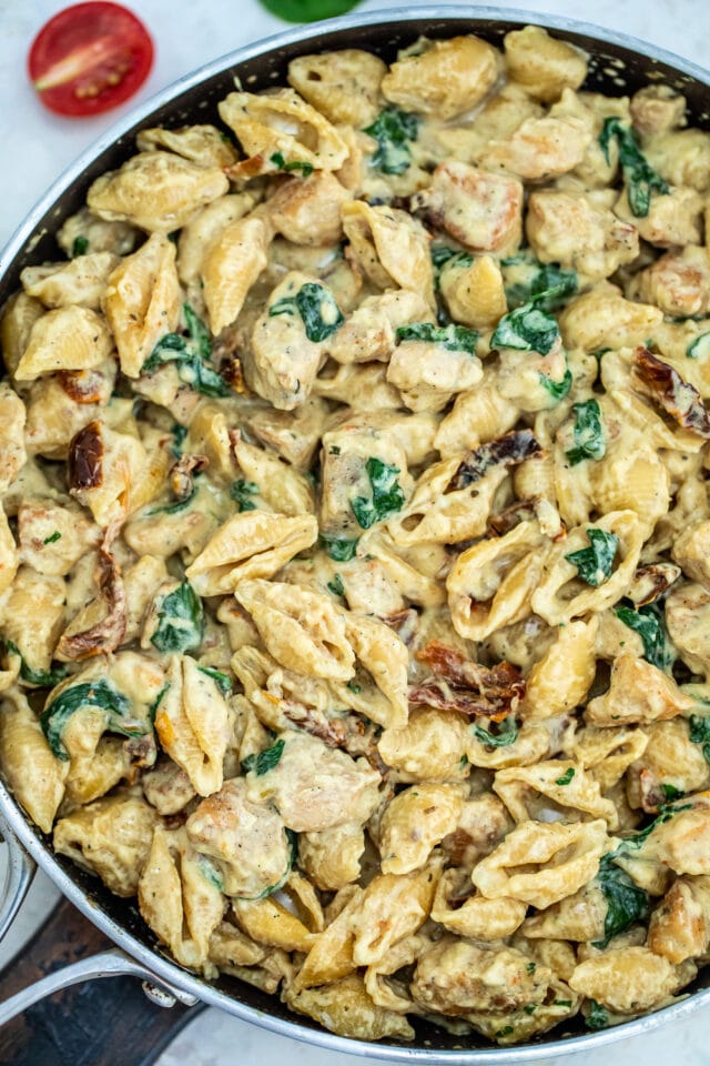 Tuscan Chicken Pasta is a quick and easy one-pan dish made with crispy chicken, sun-dried tomatoes, shell pasta, and soaked in a creamy white sauce. #pasta #tuscanchicken #chickenrecipes #30minutemeals #onepotmeals