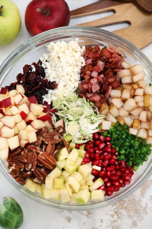 Brussels Sprouts Salad is a quick and easy side dish made with shredded brussels sprouts, crispy apples, cranberries, pomegranate arils, feta cheese, and pecans. #salad #thanksgiving #christmasrecipes #sidedish #30minutemeals