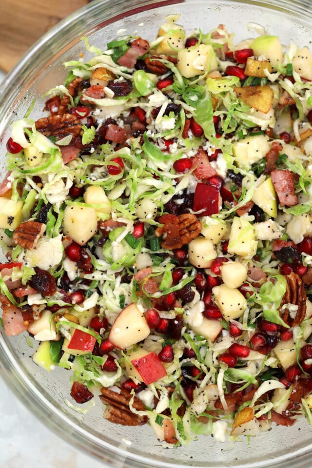 Brussels Sprouts Salad is a quick and easy side dish made with shredded brussels sprouts, crispy apples, cranberries, pomegranate arils, feta cheese, and pecans. #salad #thanksgiving #christmasrecipes #sidedish #30minutemeals