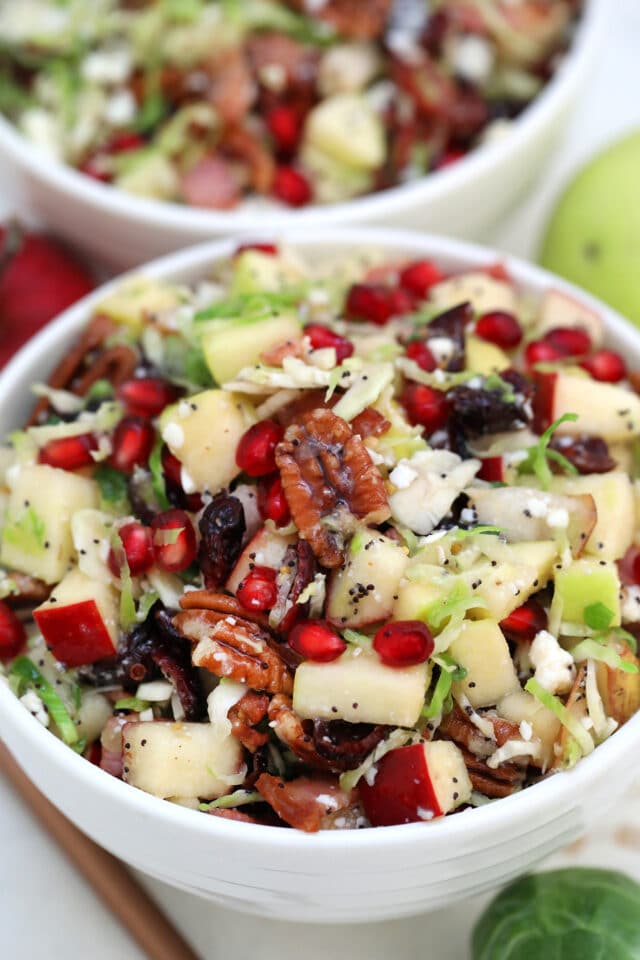 Brussels Sprouts Salad is a quick and easy side dish made with shredded brussels sprouts, crispy apples, cranberries, pomegranate arils, feta cheese, and pecans. #salad #thanksgiving #christmasrecipes #sidedish #30minutemeals