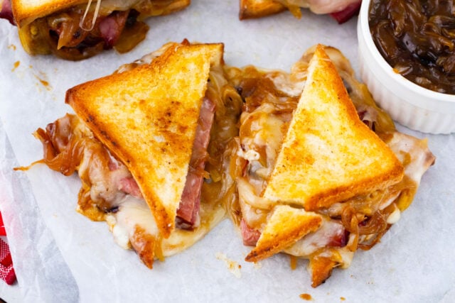 French dip grilled cheese sandwich cut in half, showing the gooey melted provolone and roast beef filling.
