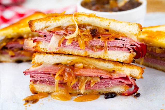 French dip grilled cheese sandwich cut in half showing layers of roast beef, provolone, and caramelized onions.