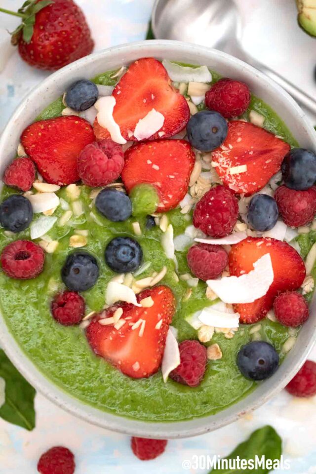 green smoothie bowl with berries and coconut flakes