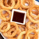 beer battered onion rings on a plate with dipping sauce
