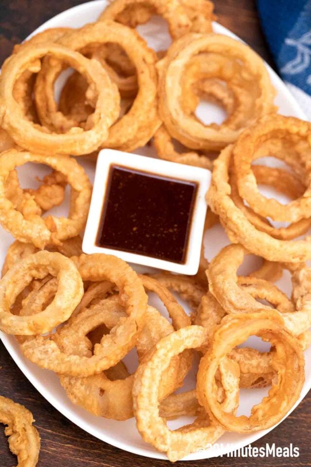 beer battered onion rings on a plate with dipping sauce