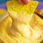 corn chip dipping in nacho cheese sauce