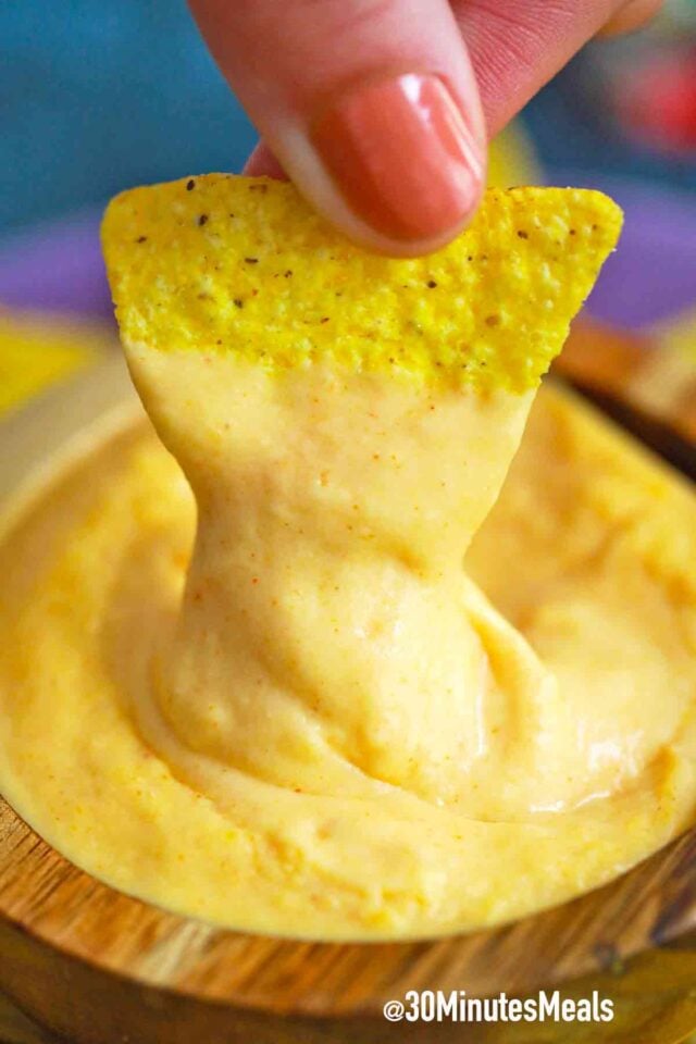 corn chip dipping in nacho cheese sauce