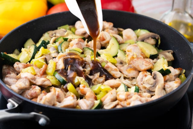 Adding sauce to almond chicken in a skillet.