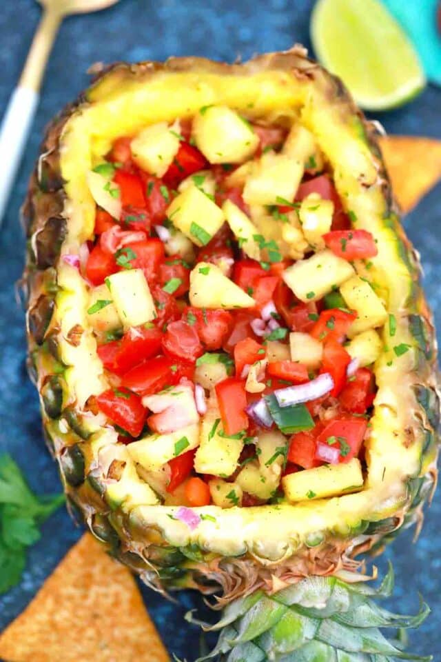a pineapple boat filled with Pineapple Mango Salsa