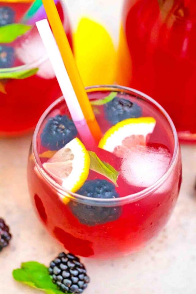a glass of blackberry lemonade with fresh blueberries and lemon