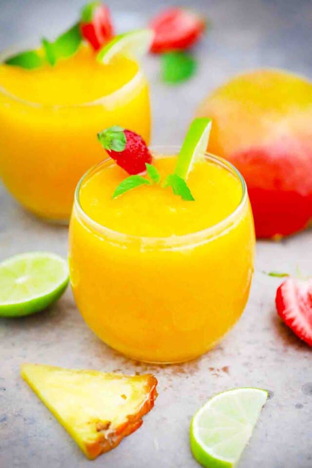 mango daiquiri in glasses garnished with mint and strawberries