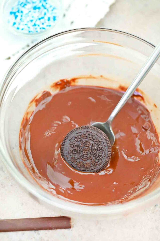 dipping an Oreo in melted chocolate