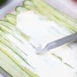 spreading cream cheese on cucumber slices
