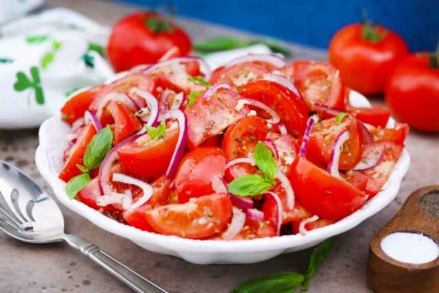 a bowl of chopped onion tomato salad with fresh basil