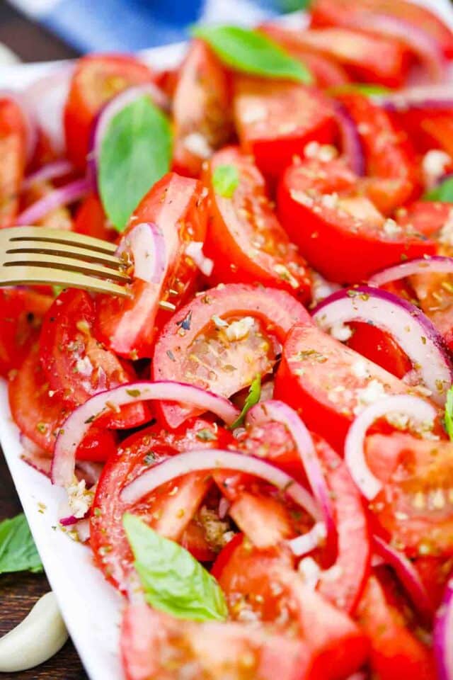 close shot of onion tomato salad and a fork into a tomato