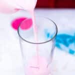 pouring pink milk into a tall glass