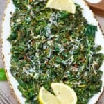 overhead shot of a serving plate with sauteed spinach and lemon wedges