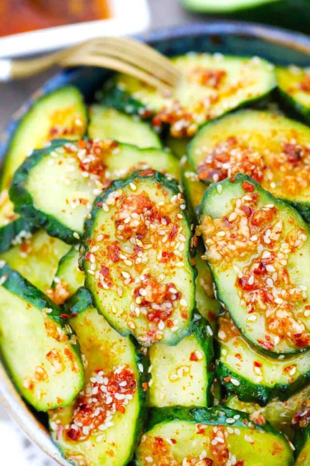a bowl of spicy asian cucumber salad with a fork next to it