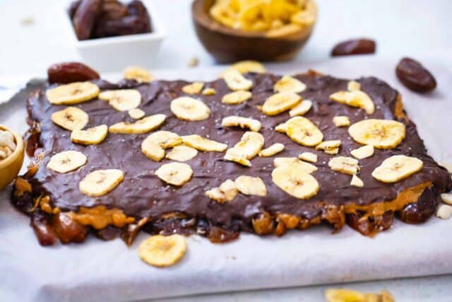 peanut butter date bark on a cutting board covered with parchment paper