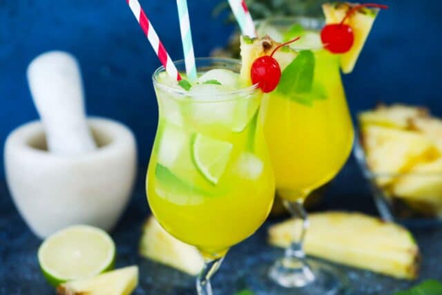 two glasses of pineapple mojito served with maraschino cherries