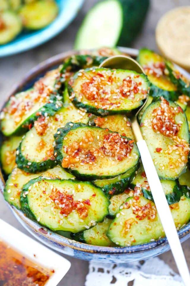 a bowl of spicy cucumber salad with a spoon in it