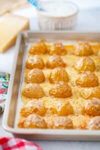crispy parmesan potatoes on a parmesan blanket on a baking sheet