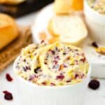 a ramekin with cranberry honey butter and sliced bread next to it