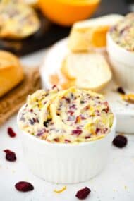 a ramekin with cranberry honey butter and sliced bread next to it