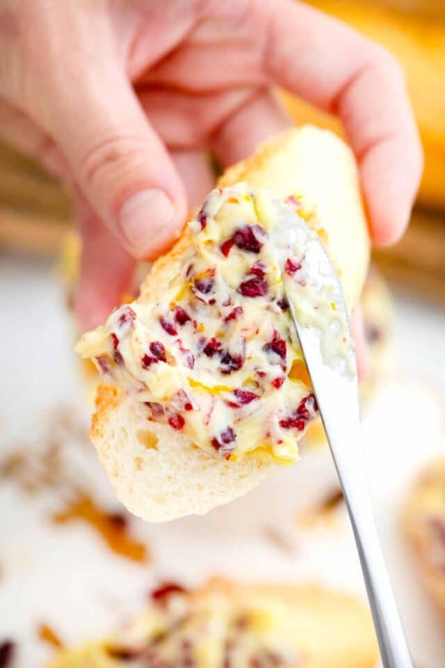 spreading cranberry honey butter on a slice of white bread