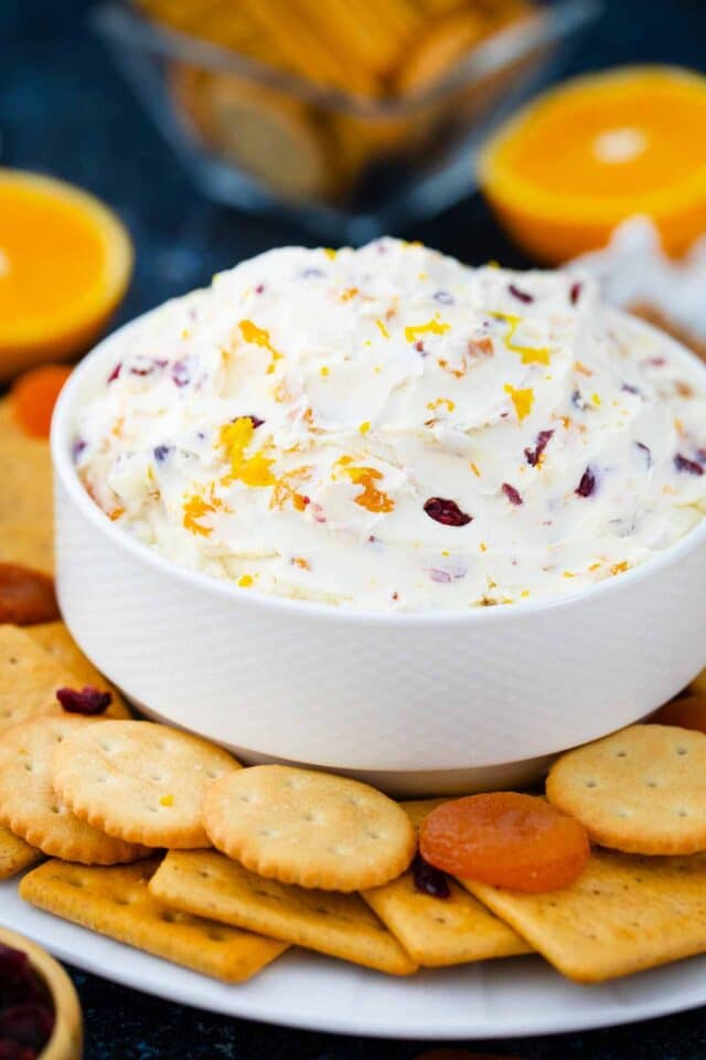 a bowl of cranberry cream cheese surrounded by crackers and dried apricots