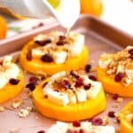 pouring honey on top of butternut squash rounds topped with sliced brie and walnuts