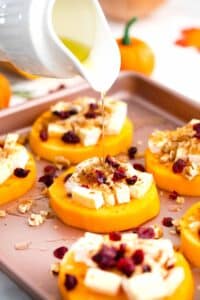 pouring honey on top of butternut squash rounds topped with sliced brie and walnuts