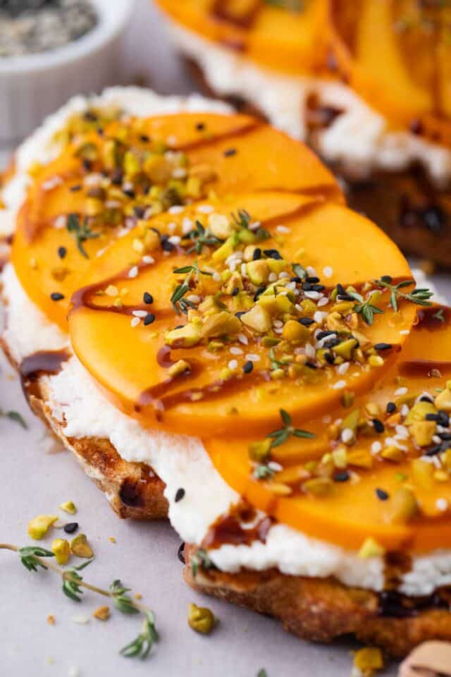 homemade persimmon toast with sourdough bread, ricotta, balsamic reduction and chopped pistachios