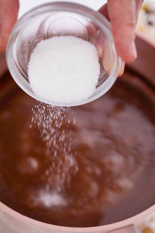 adding sugar to a saucepan with hot chocolate