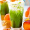 A glass of iced peach matcha freddo with peach puree.