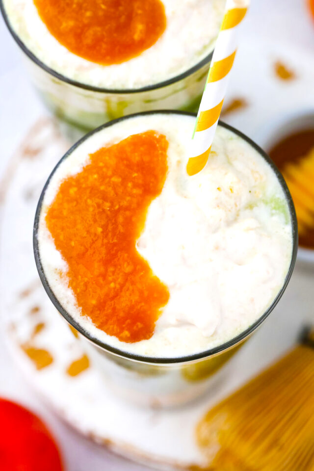 Overhead shot of iced peach matcha freddo with peach puree.
