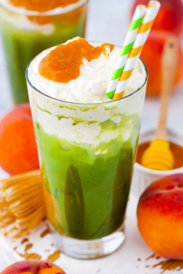 Two glasses of homemade iced peach matcha freddo with peach puree.